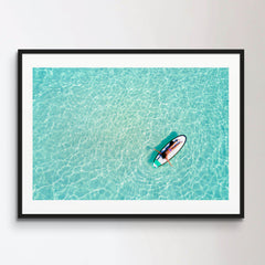 Aerial view of a woman on a surfboard in the turquoise waters