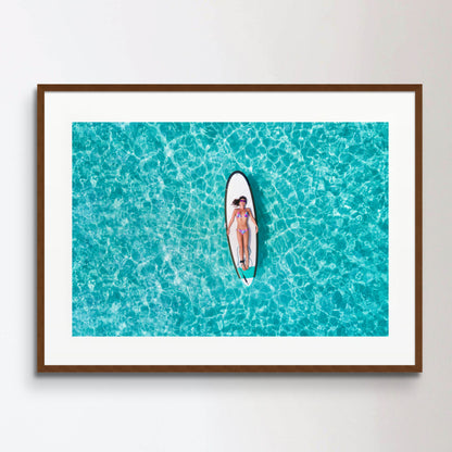 Woman in bikini is sunbathing on a surfboard