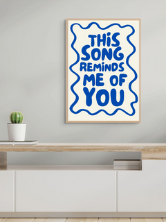 Aesthetic wall art print saying 'This song reminds me of you' framed on a modern shelf.