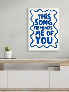 Stylish wall art print featuring the phrase 'This song reminds me of you' in bold blue letters on a cream background.