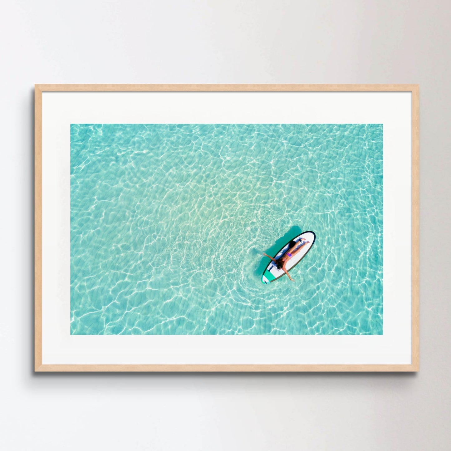 Aerial view of a woman on a surfboard in the turquoise waters