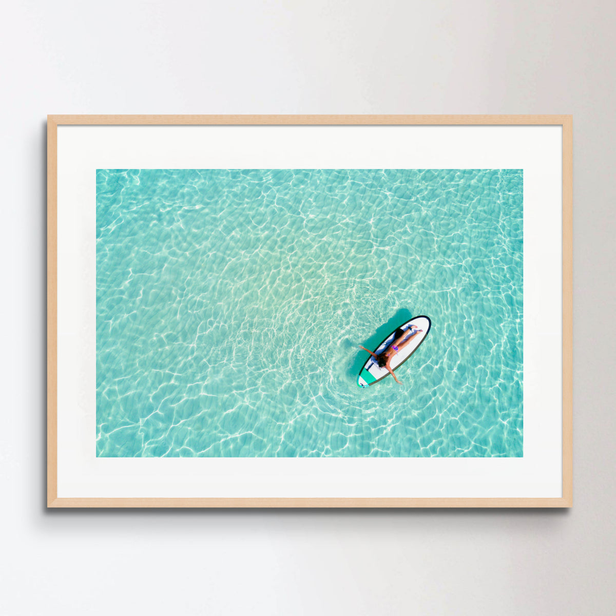 Aerial view of a woman on a surfboard in the turquoise waters