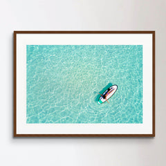 Aerial view of a woman on a surfboard in the turquoise waters