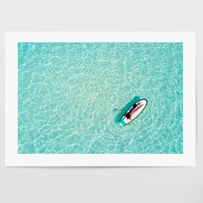 Aerial view of a woman on a surfboard in the turquoise waters